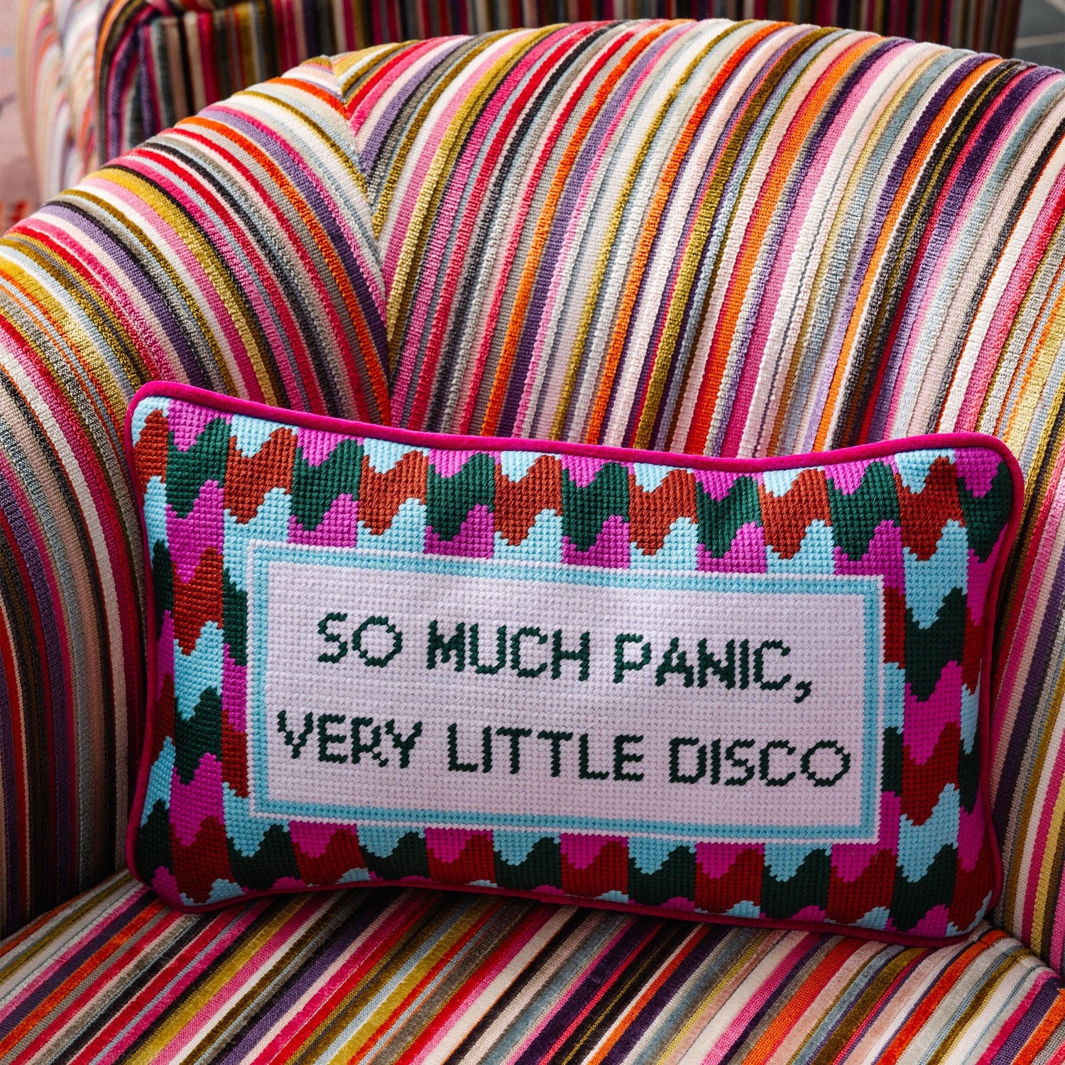 Colorful pillow with text on a multicolored striped chair