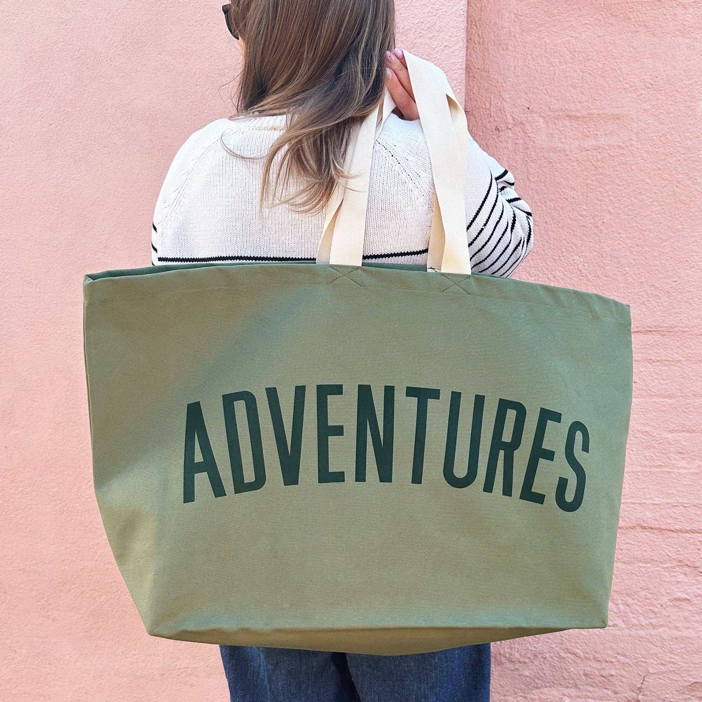 Olive green oversized canvas bag with "Adventures" text, ideal for travel and outdoor activities.