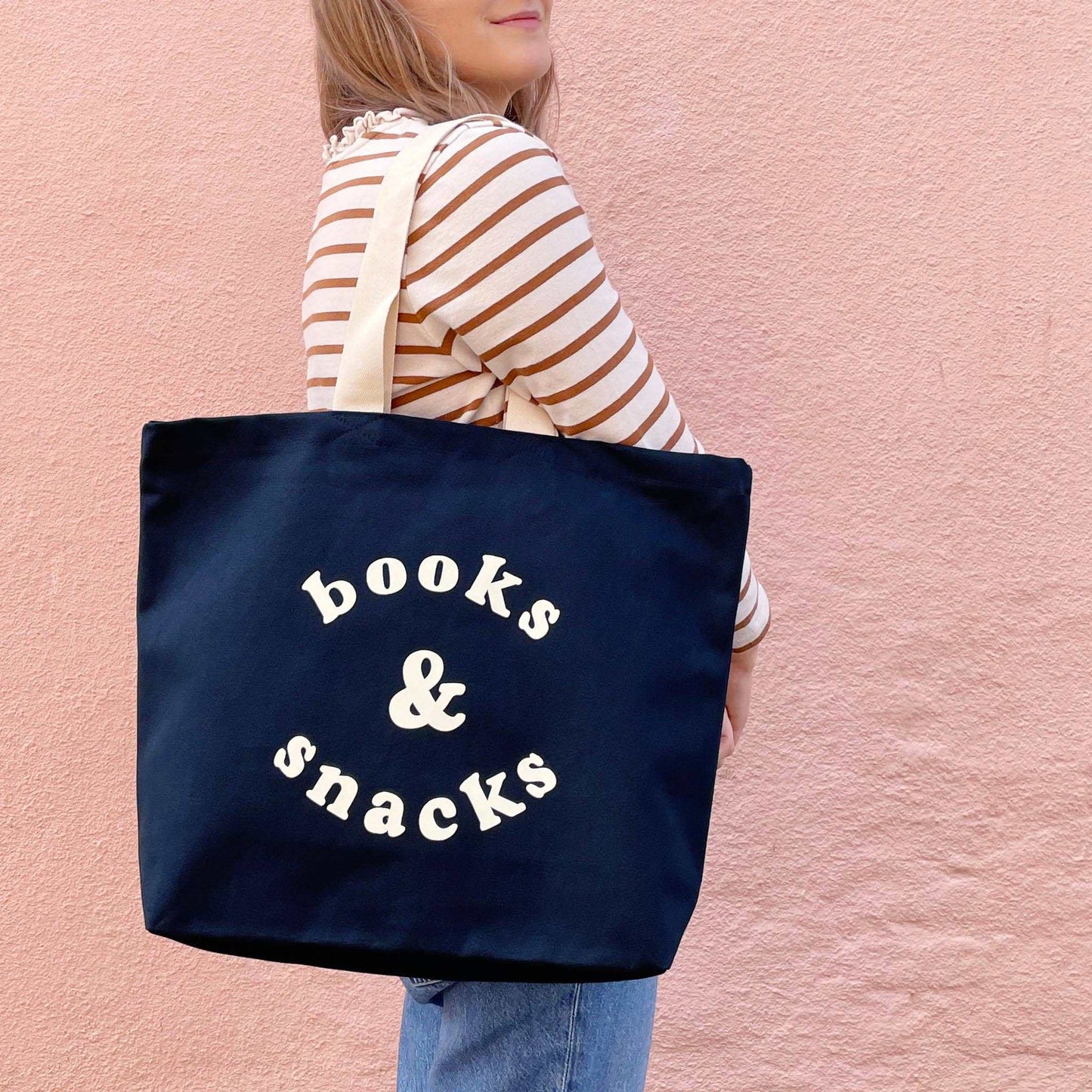 Midnight blue canvas tote bag with "books & snacks" design in off-white, perfect for carrying essentials.