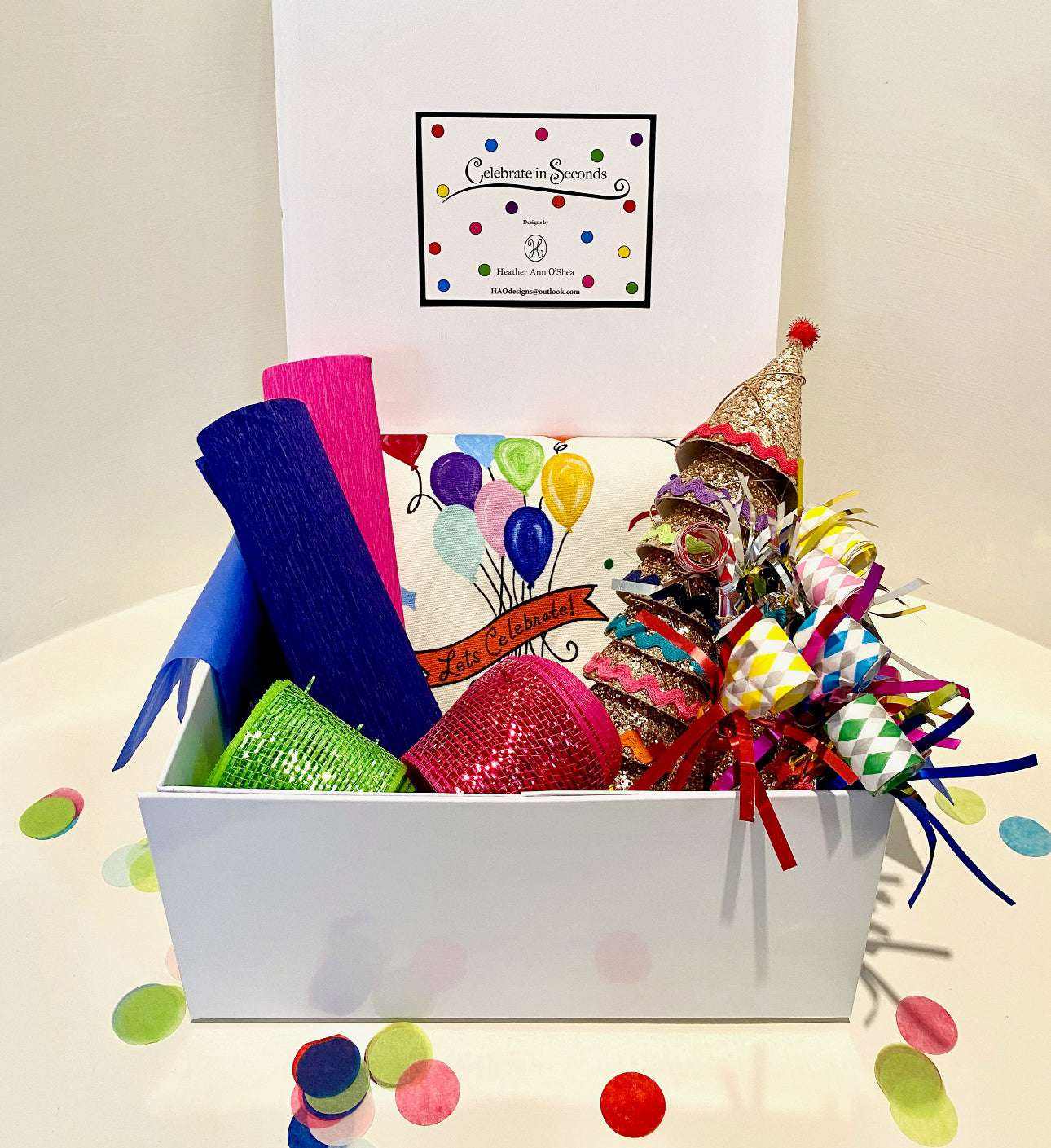 Celebration Box with festive decorations, table runner, party hats, horns, glitter ribbons, and confetti for holidays and birthdays.