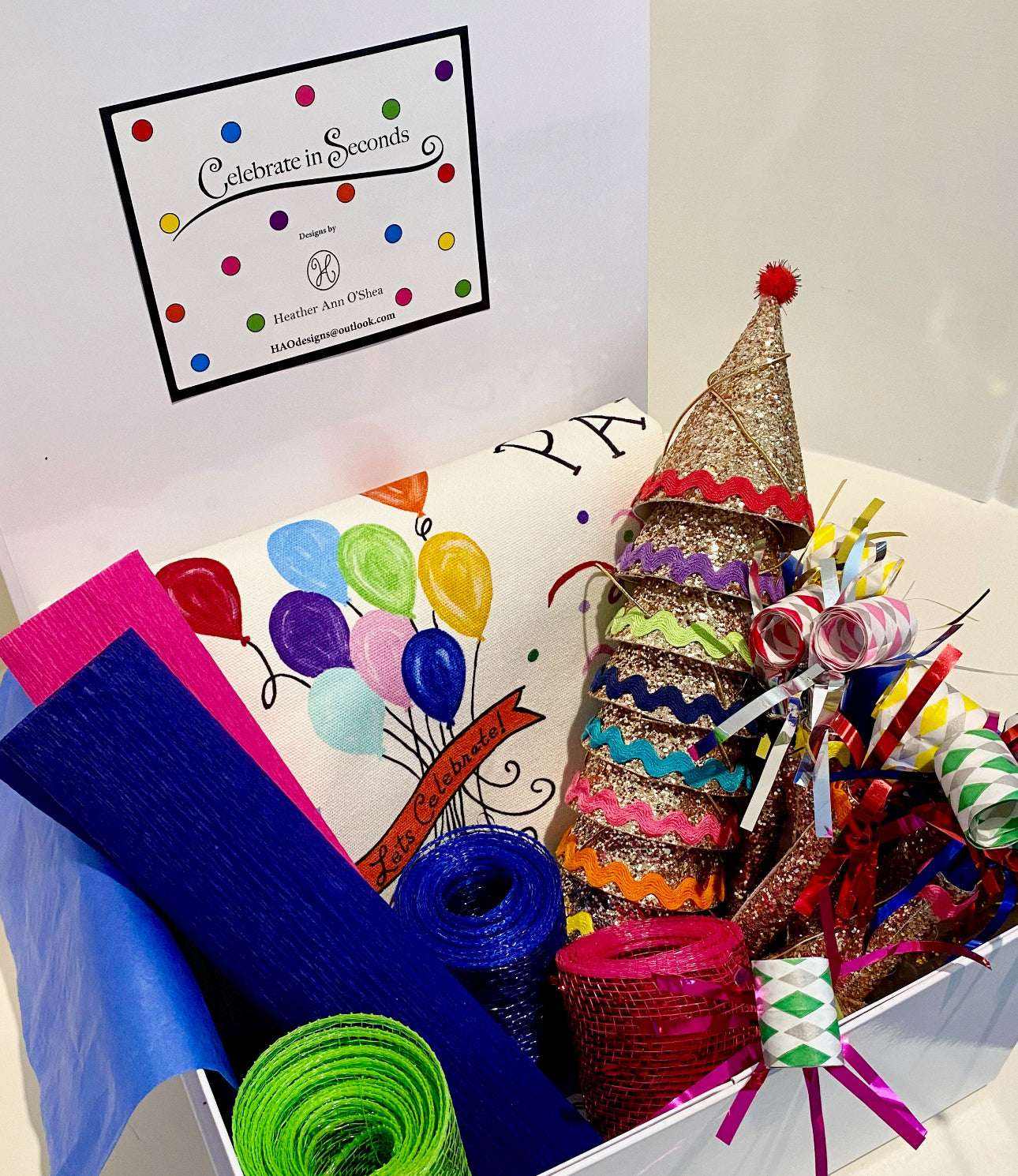 Celebration Box with heirloom decorations, including fabric hats, party horns, ribbons, and confetti.