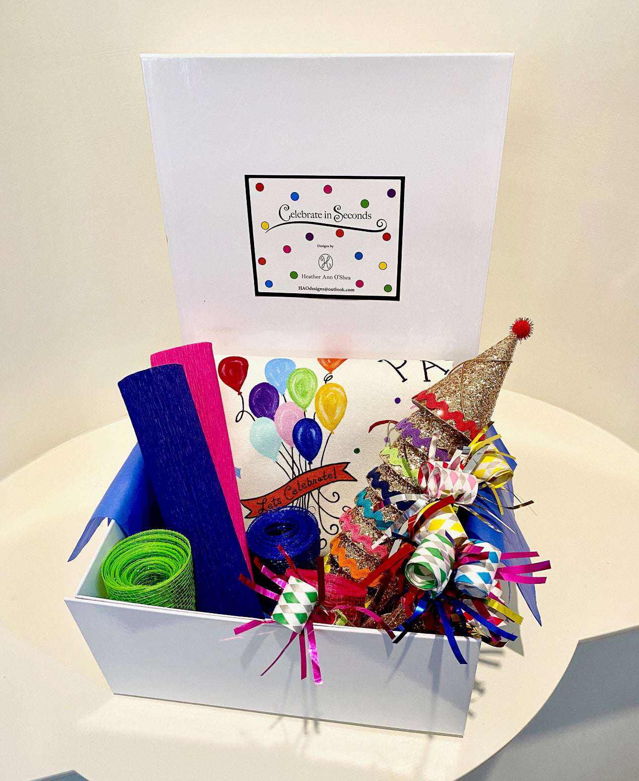 Celebration Box with party decorations, including fabric hats, party horns, ribbons, and confetti.