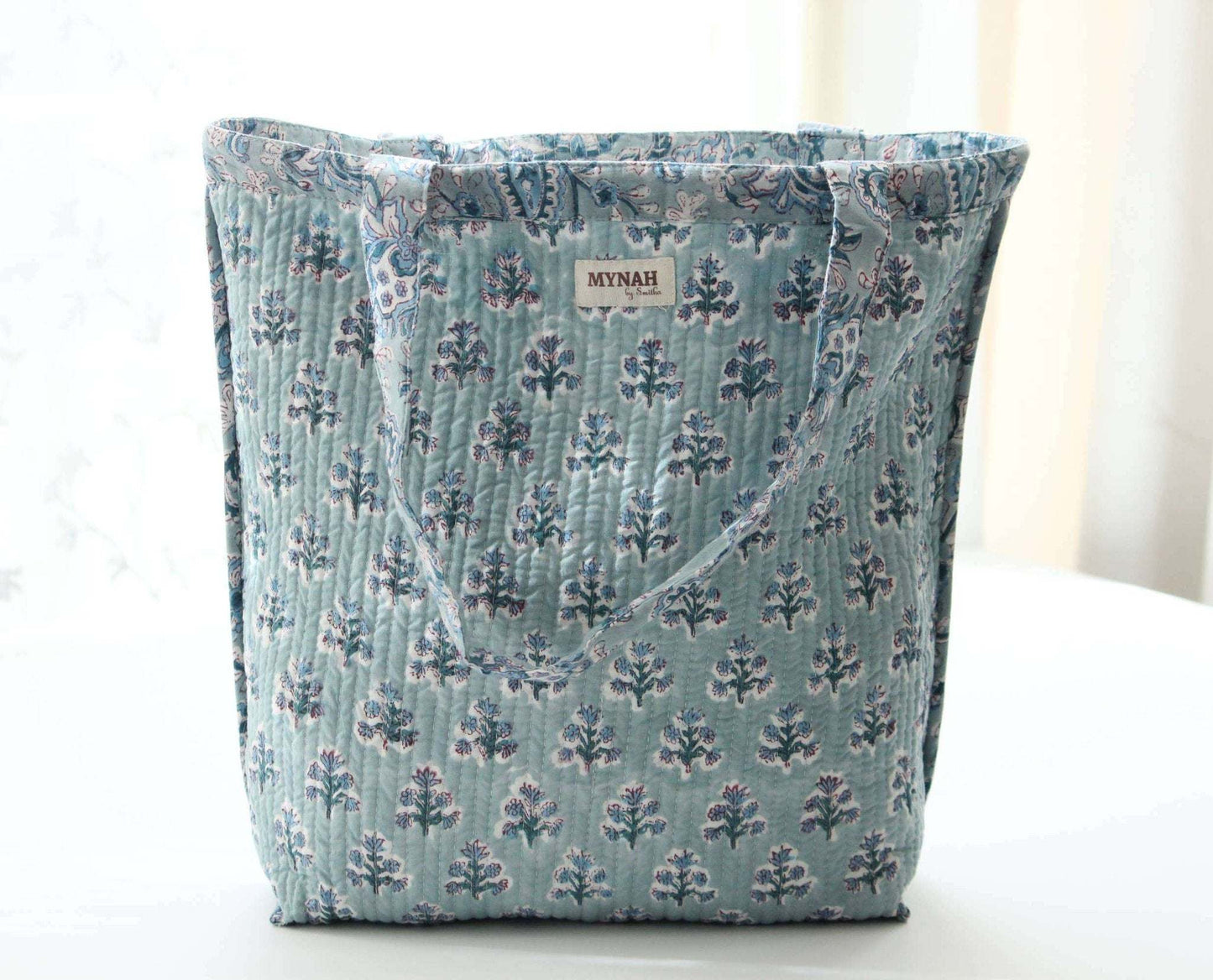 Dusty blue floral print reversible tote bag with quilted design, suitable for small laptops.