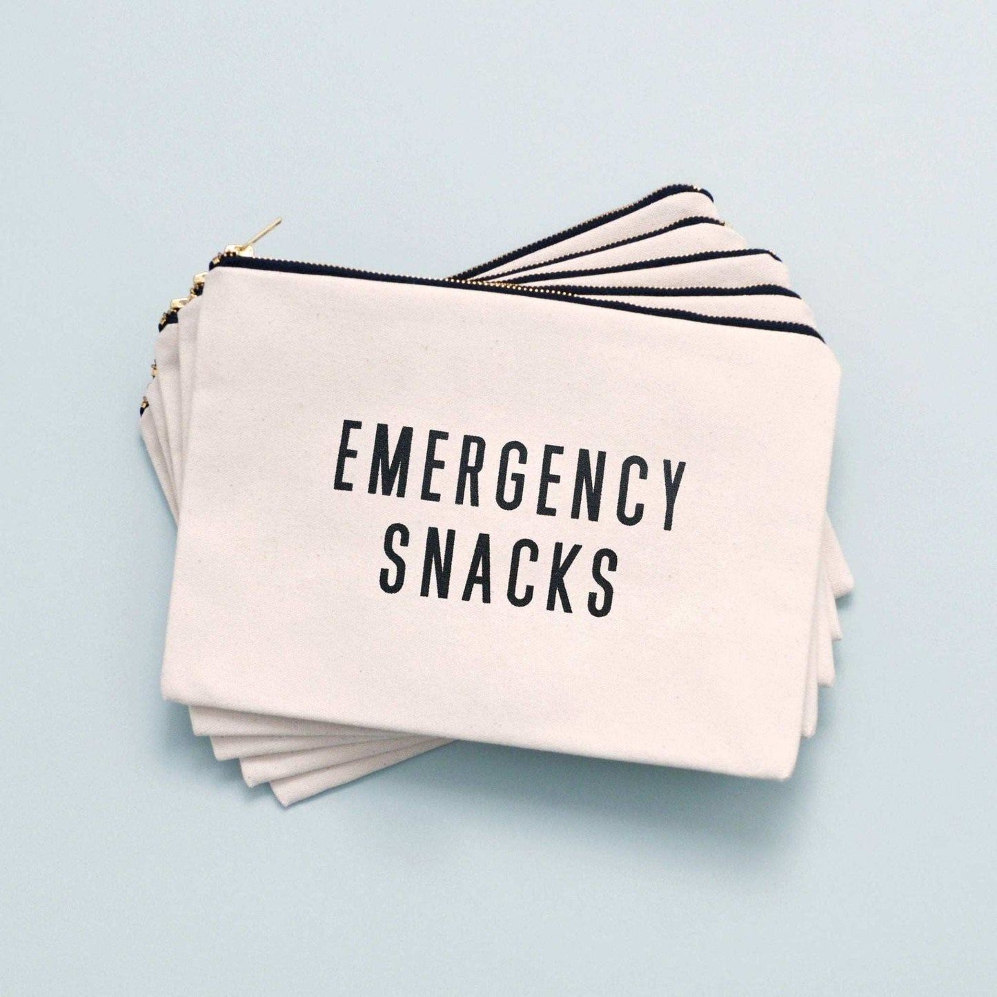 Large canvas pouch with "Emergency Snacks" text, black print, natural canvas, gold zip.