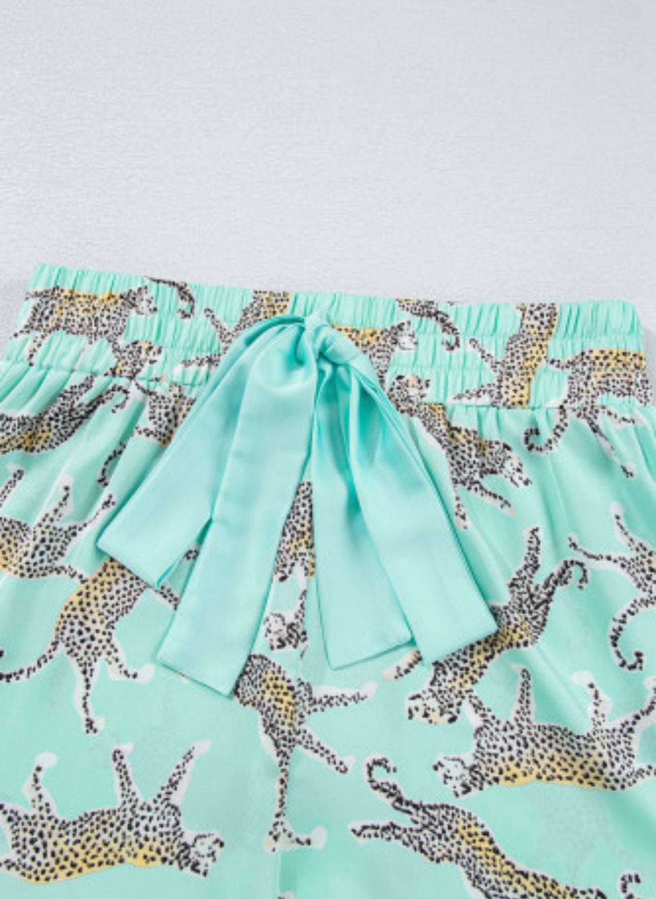 Green leopard satin ruffle shorts with ribbon detail.