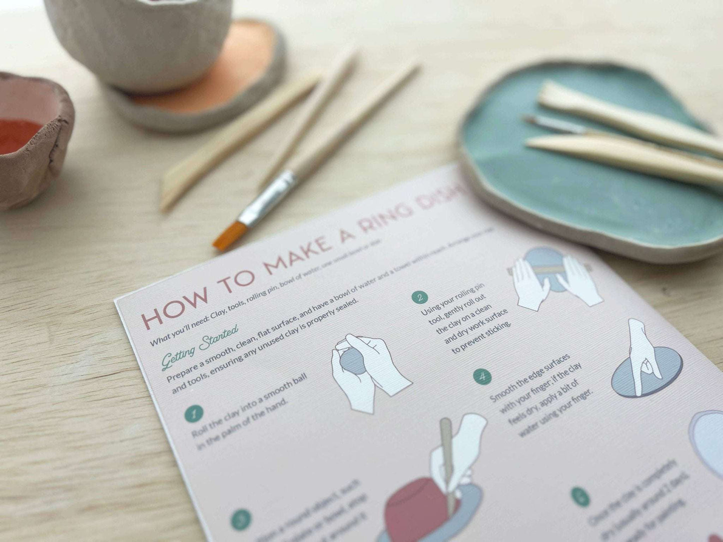 Meditative Art Clay Kit with tools, instructions, and paint brushes on a wooden table.
