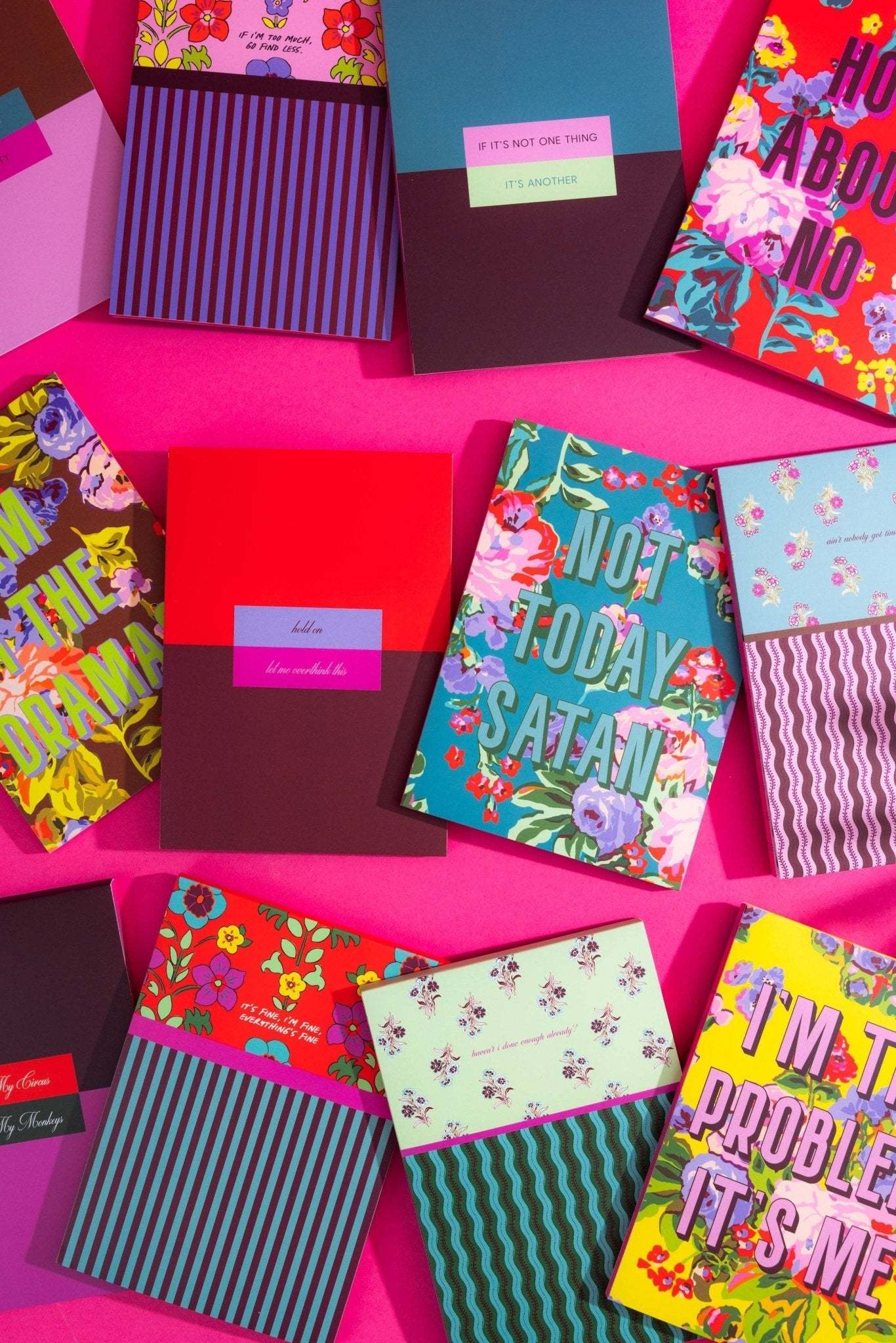 Colorful tear off notepads with vibrant designs and quotes on a pink background.