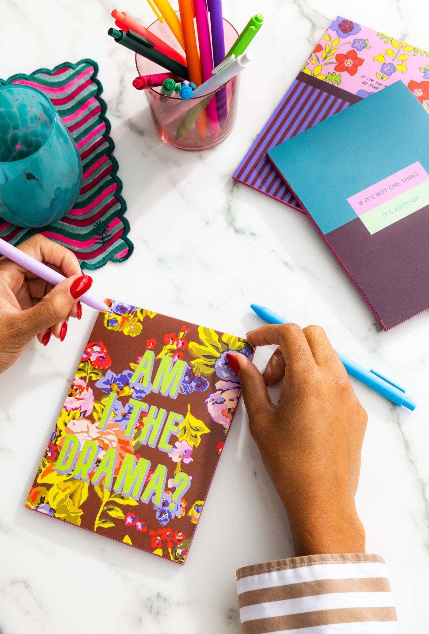 Colorful tear off notepads with floral design on a desk with pens and accessories.