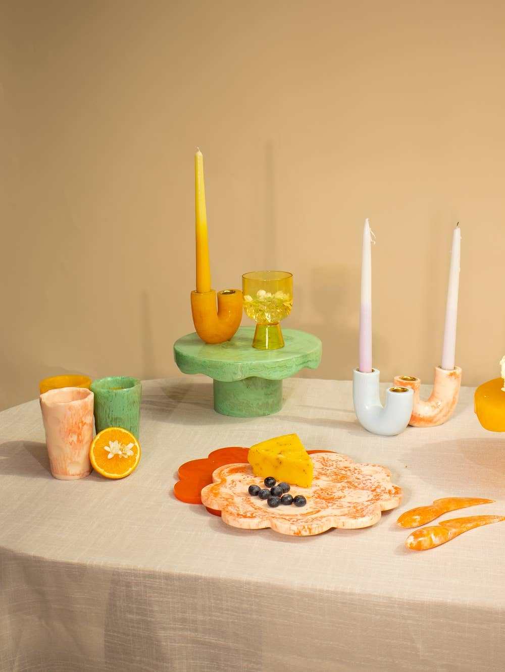 Scallop ivory pink resin cheese charcuterie board with candles on table setting.