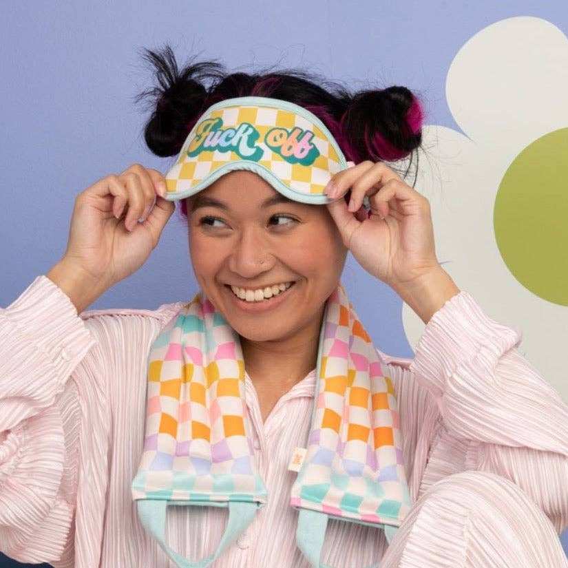 Colorful sleep mask with checkered pattern and playful lettering.