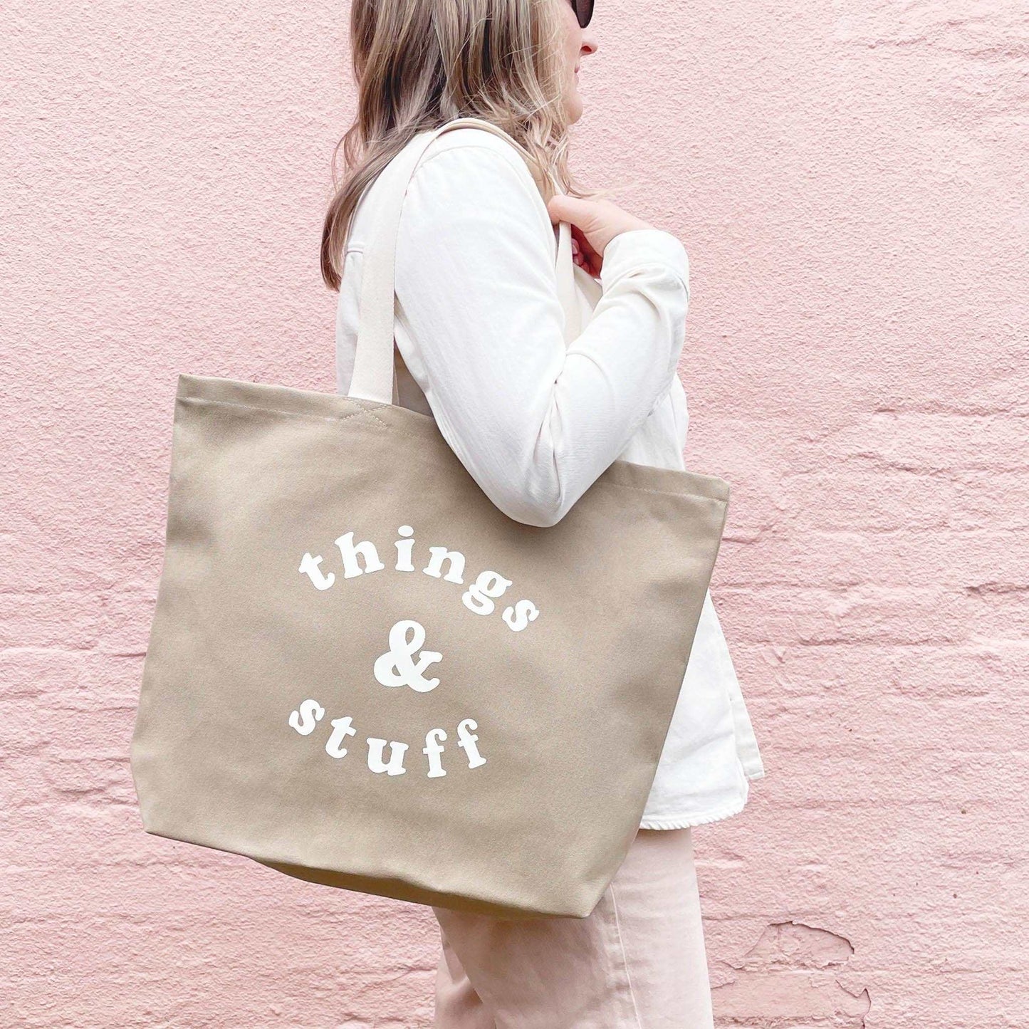 Stone canvas tote bag with "Things & Stuff" design, carried by a person.