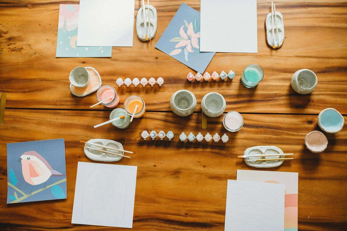 Paint by Number Kits on a wooden table with paints, brushes, and canvas, ideal for meditation and creativity.