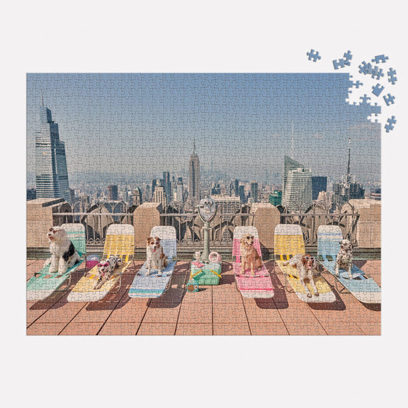 Gray Malin The Dogs of New York City 1000 Piece Puzzle featuring dogs lounging on chairs with a skyline backdrop.