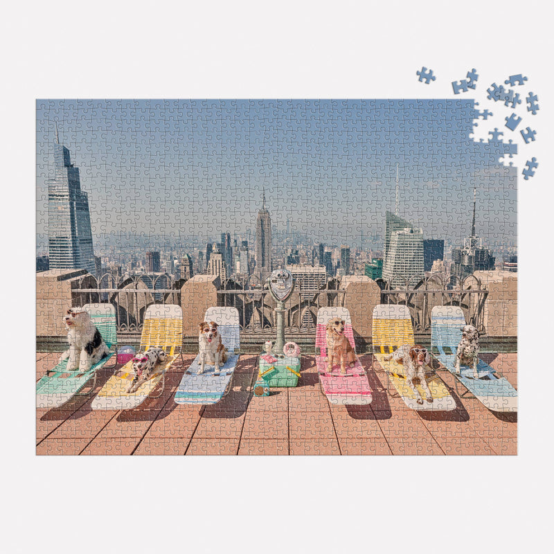 Gray Malin The Dogs of New York City 1000 Piece Puzzle featuring dogs lounging on chairs with a skyline backdrop.