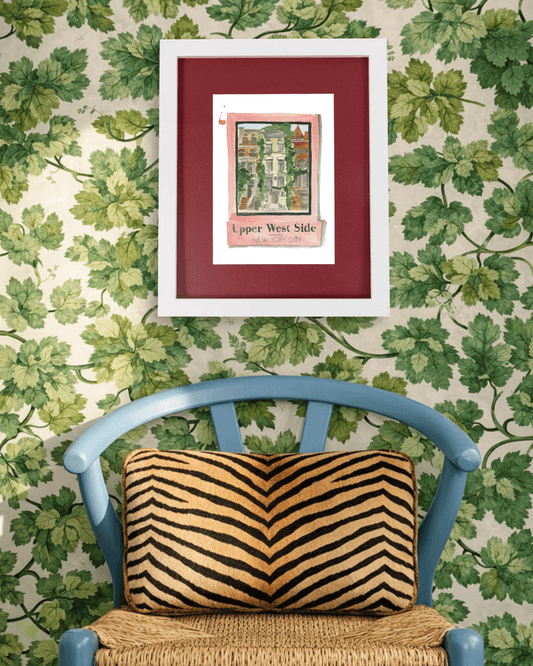 Framed artwork on a wall with decorative green leaf pattern, blue chair with tiger-striped pillow.