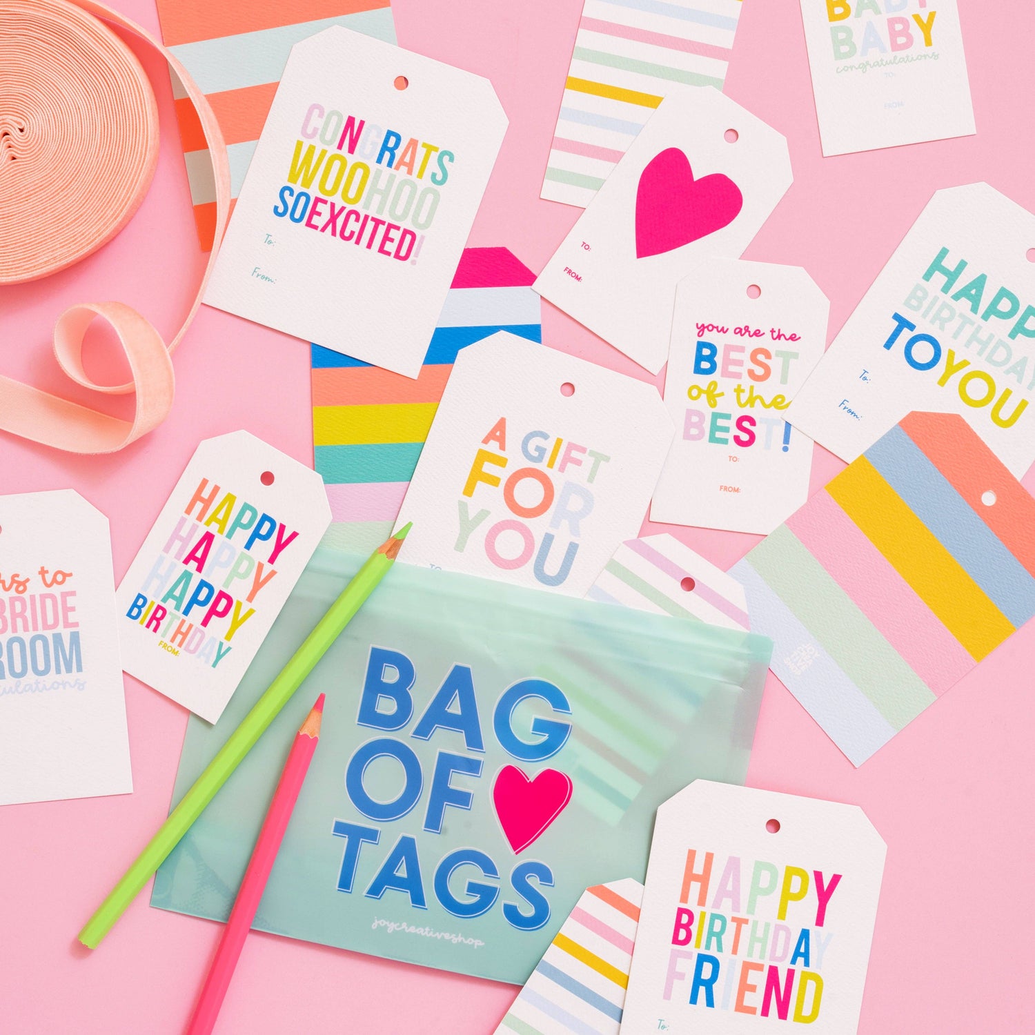 Colorful gift tags and a notebook titled 'Bag of Tags' on a pink background