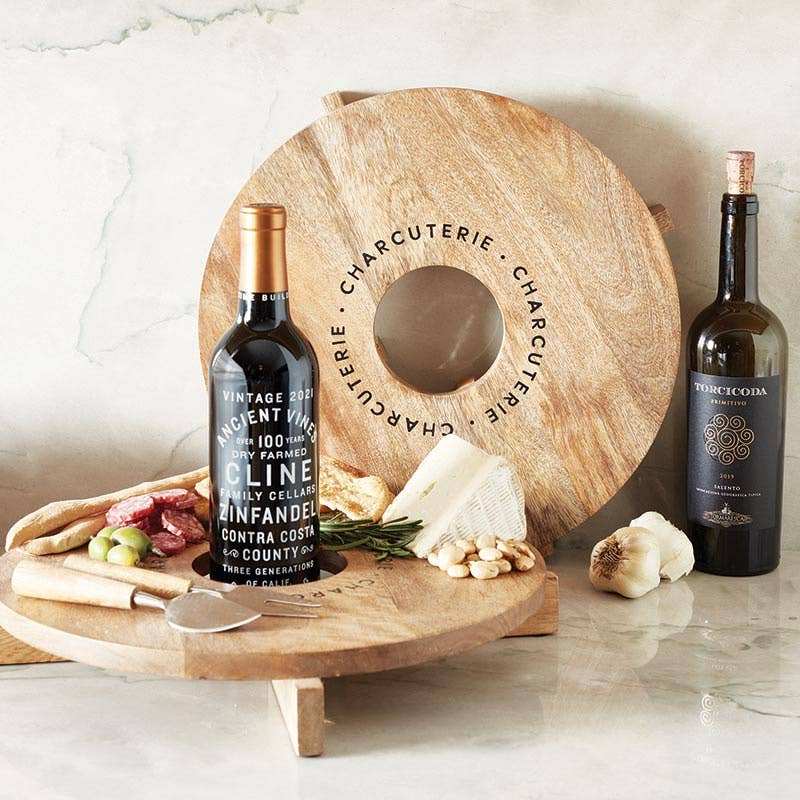 Santa Barbara Design Studio charcuterie board with wine holder featuring wine bottles and assorted snacks.