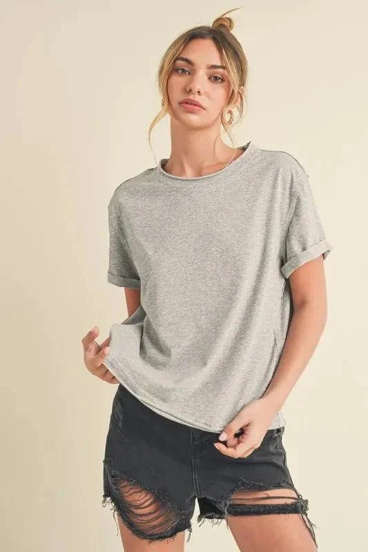Aemi + Co Exposed Seam Round Neck Short Sleeve T-Shirt in gray, styled with distressed black shorts, featuring visible seam detailing.