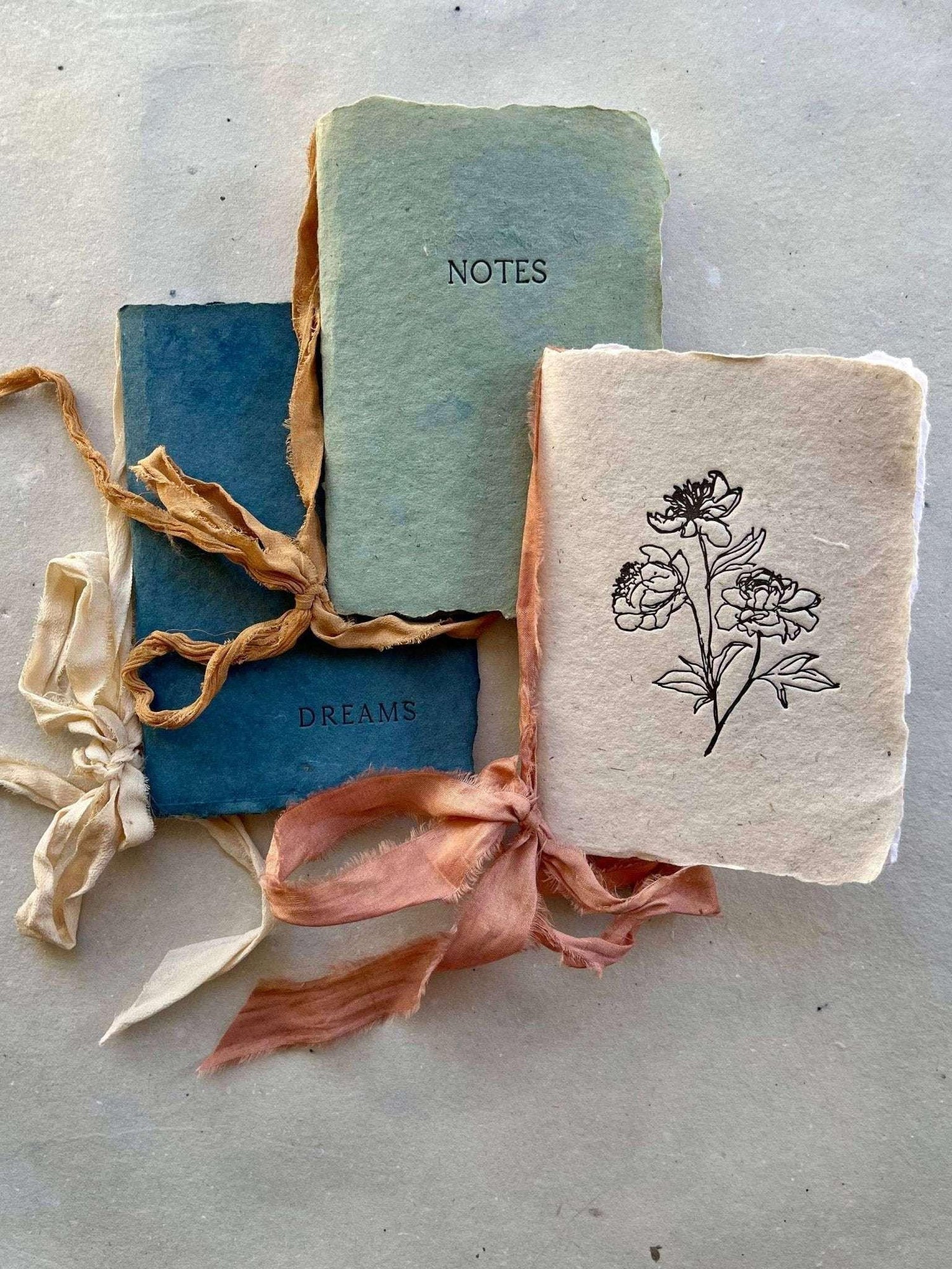 Artisan made small notebooks with silk ribbons, floral design, and handmade paper.