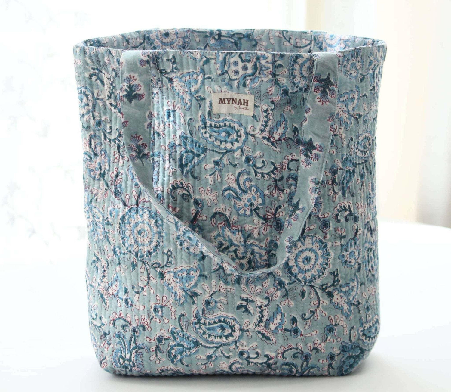 Dusty blue floral print reversible tote bag with quilted design.