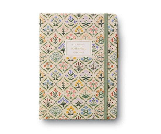 Rifle Paper Co. Estee Journal with floral design, elastic band, fabric cover, and a gold pen attached.