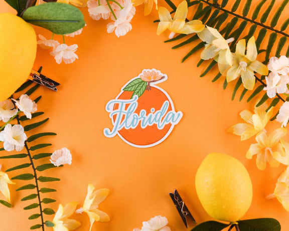 Florida Orange Sticker with floral design on orange background.