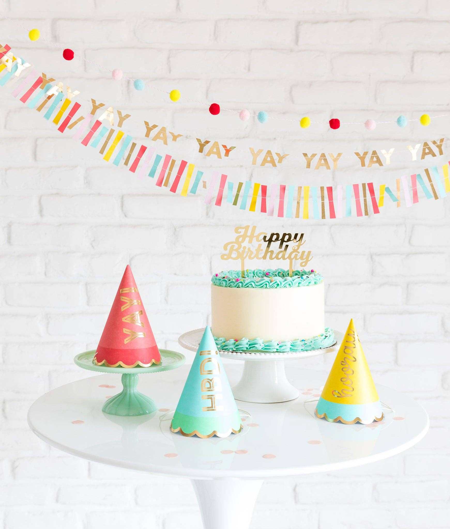 Hip Hip Hooray party hats with gold foil accents on a white table setting.