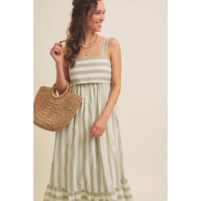 Stripe MIDI dress with back ribbon tie, sleeveless, in a light color, worn by model holding a straw bag.