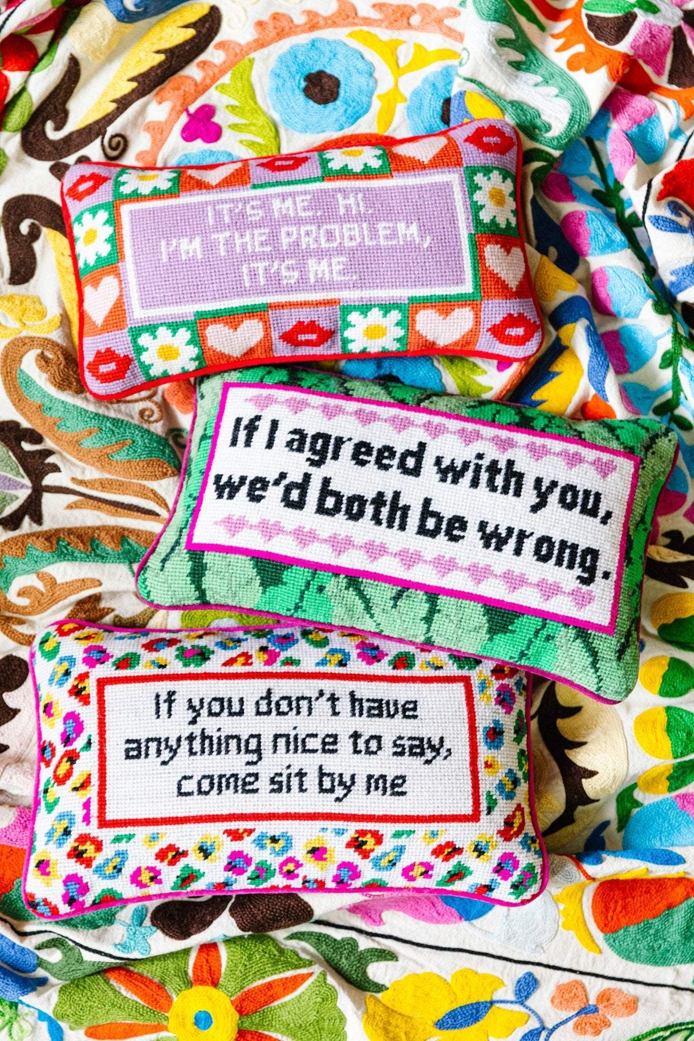 Needlepoint pillow with humorous sayings, embroidered on the front, backed with red velvet, colorful designs.