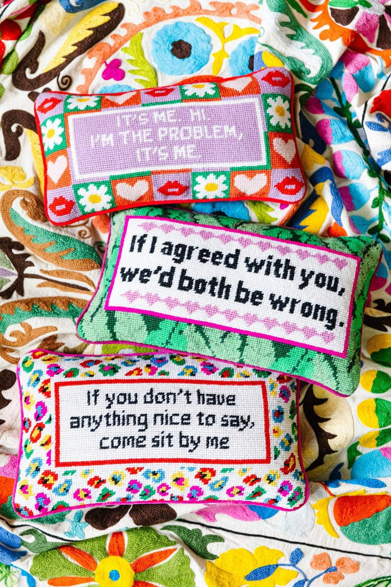 Needlepoint pillow with humorous sayings, embroidered on the front, backed with red velvet, colorful designs.