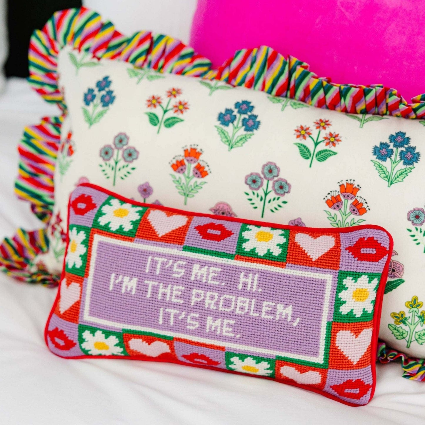Needlepoint pillow with colorful design and embroidery text, backed in red velvet.