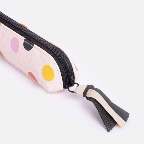 Pale pink dotty pencil case with colorful spots, chunky contrast zip, and monochrome grosgrain ribbon pull.