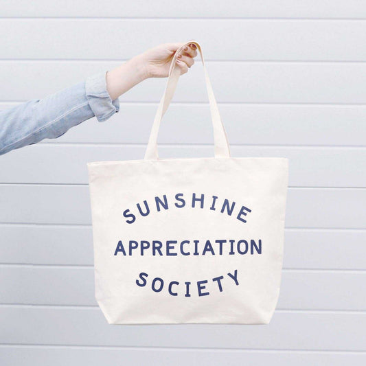 Sunshine Appreciation Society big canvas tote bag with navy blue print and mid-length handles.